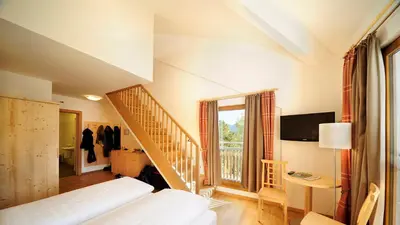 a bedroom with a bed and a staircase with a window at Hotel Masatsch in Caldaro
