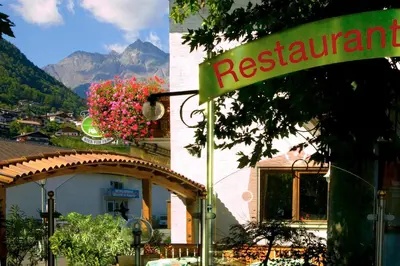 a restaurant sign in front of a building with flowers at Gasthof Anny in Marlengo