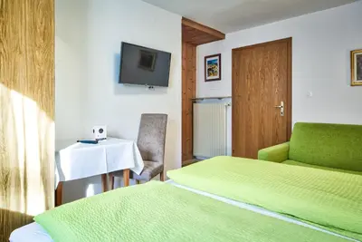 a room with two beds and a television and a table at Gasthof Anny in Marlengo