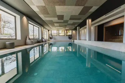 a swimming pool with a blue tile floor and windows at Thalguter - Rooms & Breakfast in Lagundo