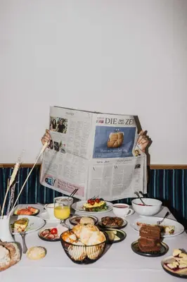 a table topped with plates of food and a newspaper at Thalguter - Rooms & Breakfast in Lagundo