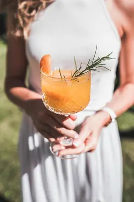 a woman in a white dress holding a drink at Thalguter - Rooms & Breakfast in Lagundo