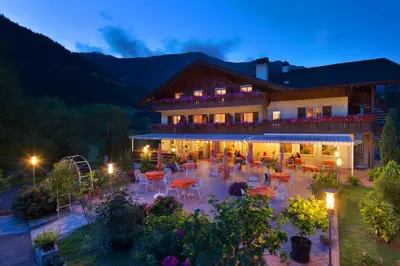 a building with a patio with tables and chairs at night at Hotel Klotz in San Leonardo in Passiria