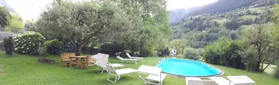 a group of chairs and a swimming pool in the grass at Hotel Klotz in San Leonardo in Passiria
