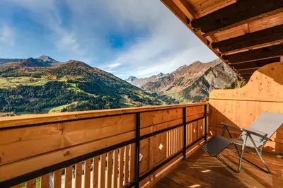 a chair on a balcony with mountains in the background at Hotel Kronhof in Moso