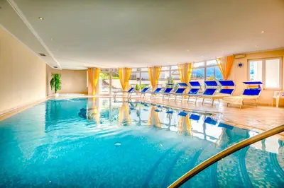 a large swimming pool in a hotel with blue chairs at Hotel Kronhof in Moso