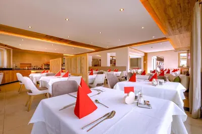 a dining room with white tables and red chairs at Hotel Kronhof in Moso