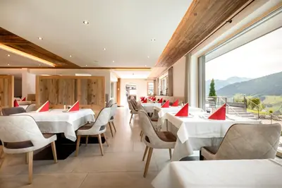 a restaurant with white tables and chairs and a large window at Hotel Kronhof in Moso