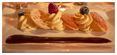a plate with a dessert with fruit and whipped cream at Hotel Kronhof in Moso