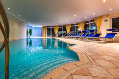 a swimming pool in a hotel with blue chairs at Hotel Kronhof in Moso