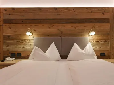a bed with white sheets and pillows in a room at Residence Rautal B&B ***S in San Vigilio Di Marebbe