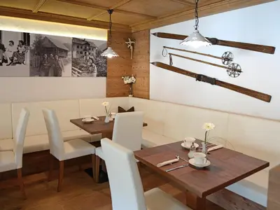 a dining room with a wooden table and white chairs at Residence Rautal B&B ***S in San Vigilio Di Marebbe