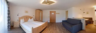 a bedroom with a large bed and a couch at Residence Rautal B&B ***S in San Vigilio Di Marebbe