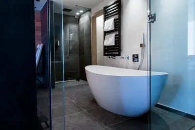 a bathroom with a tub and a glass shower at Hotel Gran Paradiso in San Cassiano