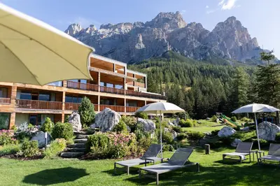 a hotel with chairs and umbrellas in the grass at Hotel Gran Paradiso in San Cassiano