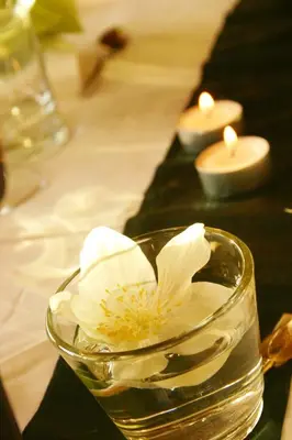 a flower in a glass bowl on a table with candles at Panoramapension Etschblick in Meltina