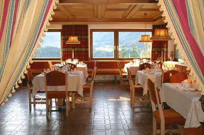 a restaurant with white tables and chairs and windows at Panoramapension Etschblick in Meltina