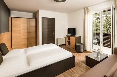 a bedroom with a large white bed and a television at Hotel Traminerhof in Termeno