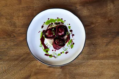 a white plate with food on a wooden table at Hotel Traminerhof in Termeno