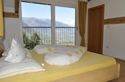 a bedroom with a bed with a large window at Ferienwohnungen Niederhof in Lana