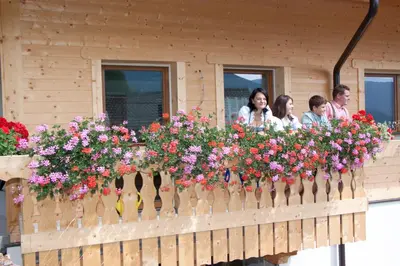 a group of people standing on a balcony with flowers at Schweinsteghof Urlaub auf dem Bauernhof in Sarntal