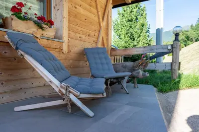 a pair of chairs and a deer on a porch at Schweinsteghof Urlaub auf dem Bauernhof in Sarntal