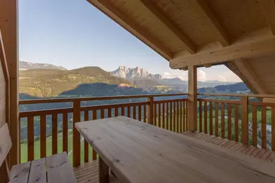 a wooden porch with a wooden table on a balcony with mountains at Frühaufhof in Barbiano