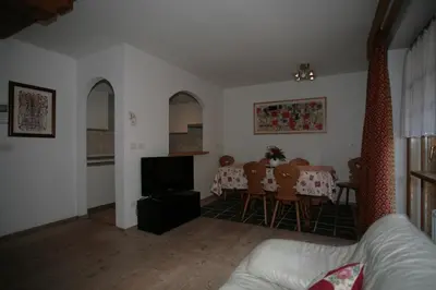 a living room with a table and a dining room at Villetta ai Pini Deluxe in Canazei