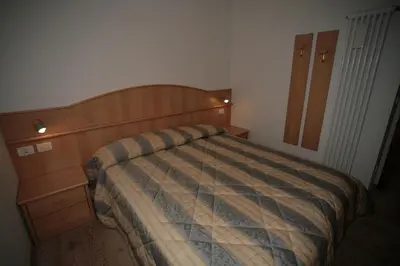 a bedroom with a bed and a wooden dresser at Villetta ai Pini Deluxe in Canazei