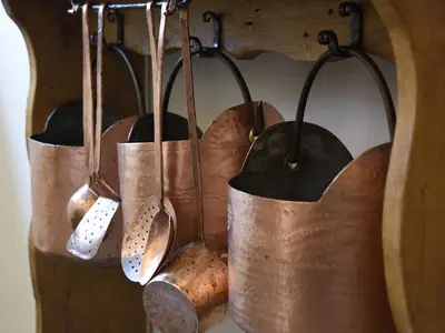 a group of copper utensils hanging on a wall at Europa Mountain Apartments in Alleghe