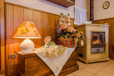 a lamp and a doll sitting on a table next to a fireplace at Albergo Genzianella in Rocca Pietore