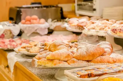 a bakery with a bunch of pastries and other foods at Albergo Genzianella in Rocca Pietore
