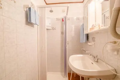 a white bathroom with a sink and a shower at Albergo Genzianella in Rocca Pietore