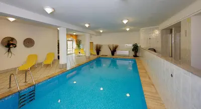 a large swimming pool in a room with yellow chairs at Appartement Riederhof in Saltusio