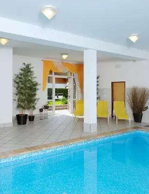 a swimming pool with yellow chairs next to a house at Appartement Riederhof in Saltusio