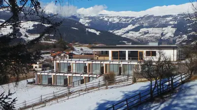 a house on a snowy hill with mountains in the background at Albergo Gasthof zur Krone in Laion