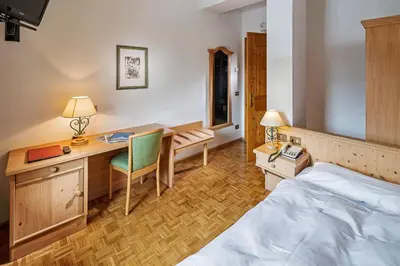 a hotel room with a bed and a desk and a bed at Hotel Piccolo Pocol in Cortina dʼAmpezzo