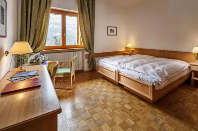 a hotel room with a bed and a desk and a desk at Hotel Piccolo Pocol in Cortina dʼAmpezzo