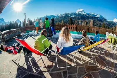 a group of people sitting in chairs by a pool at Hotel Piccolo Pocol in Cortina dʼAmpezzo