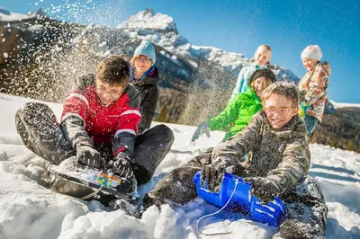 a group of people sitting in the snow with snowboards at Hotel Piccolo Pocol in Cortina dʼAmpezzo