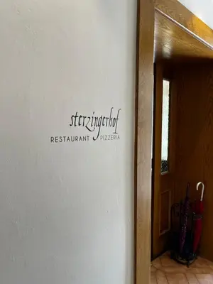 a bedroom with a bed and a living room at Gasthof Sterzingerhof in Vipiteno