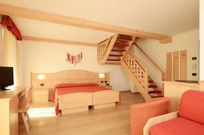 a bedroom with a bed and a staircase at Hotel La Soldanella in Moena