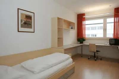 a bedroom with a bed and a desk and a window at Kolpinghaus Bolzano in Bolzano