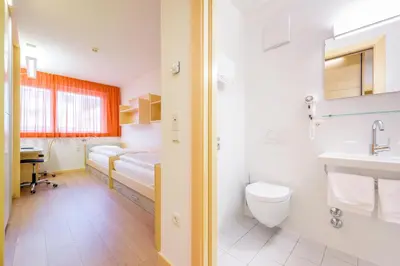 a bathroom with a bed and a sink and a toilet at Kolpinghaus Bolzano in Bolzano