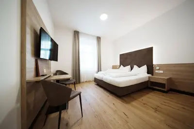 a bedroom with a bed and a desk and a television at Kolpinghaus Bolzano in Bolzano