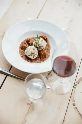 a white plate of food on a table with wine glasses at Garni Ciasa Urban in Badia