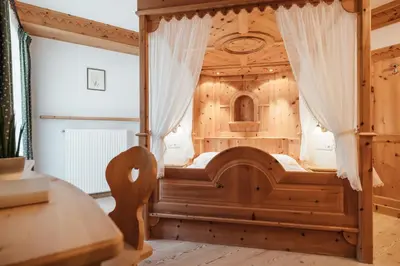 a wooden bed in a room with a table at Garni Ciasa Urban in Badia