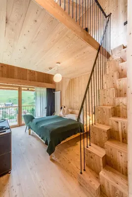 a bedroom with a green bed and a staircase at Hotel Tyrol in Funes