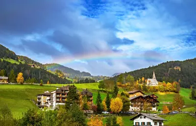 a living room with a black couch and a chair at Hotel Tyrol in Funes