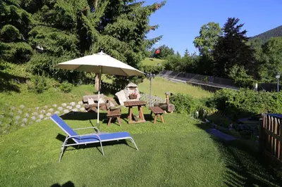 a yard with a table and chairs and an umbrella at Garni Panoramik in Ortisei